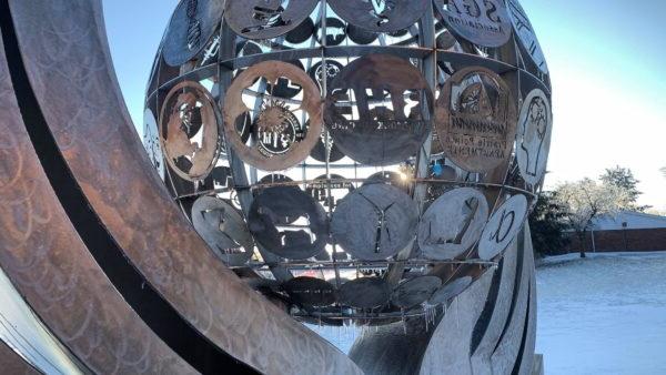 a sculpture of a sphere with persony different symbols